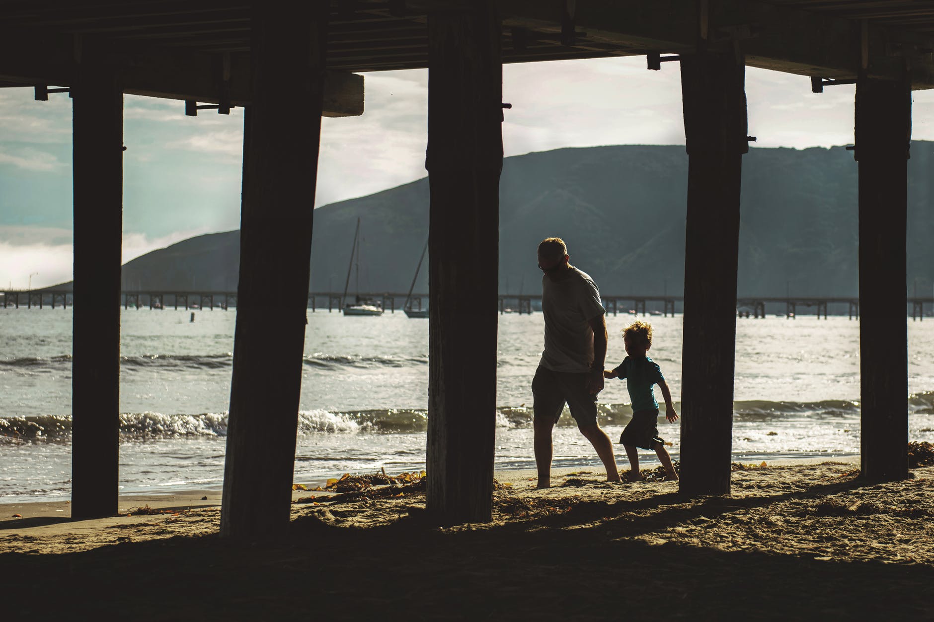 man and child walking on shore