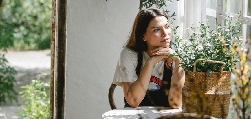 young woman sitting at table with basket of flowers